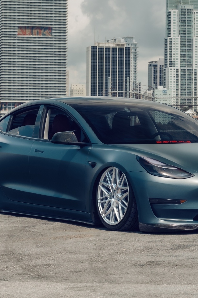 Электрокар Tesla Model 3 на фоне небоскребов