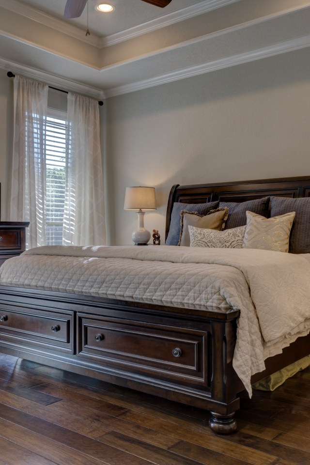 Дорогая деревянная кровать в спальной комнате