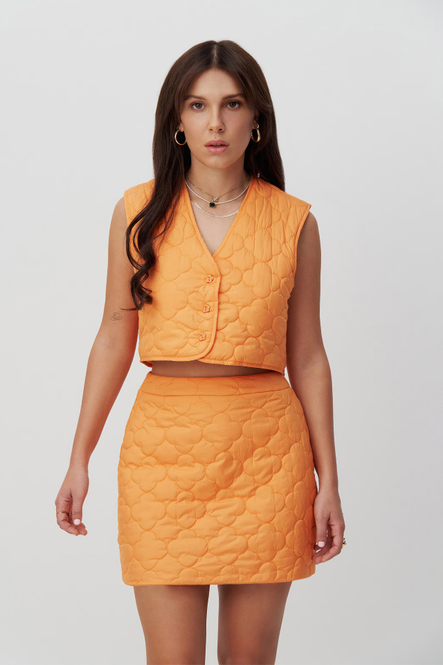 Девушка актриса Милли Бобби Браун в костюме на сером фоне