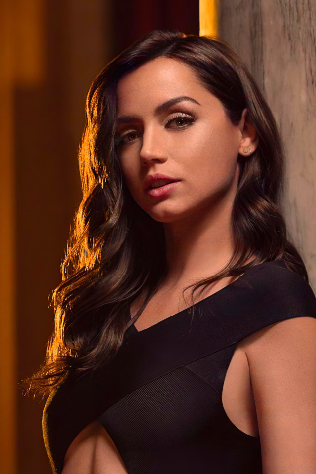 Длинноволосая актриса Ана де Армас стоит у стены