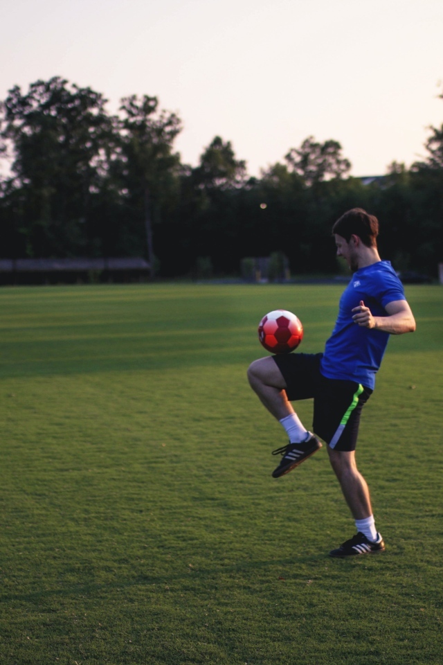 Мужчина футболист с мячом на поле