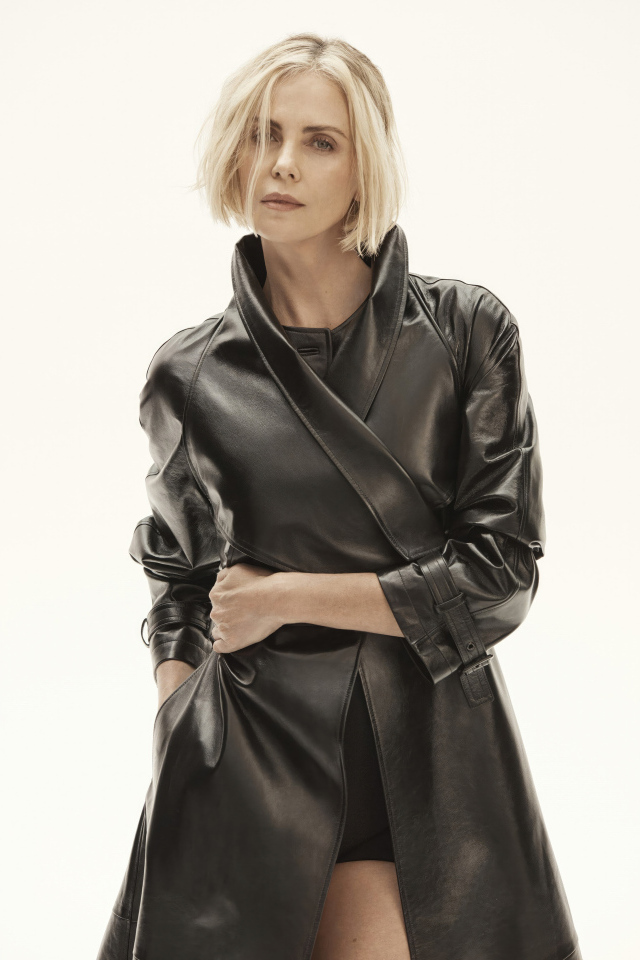 Популярная актриса Шарлиз Терон в черном плаще на белом фоне