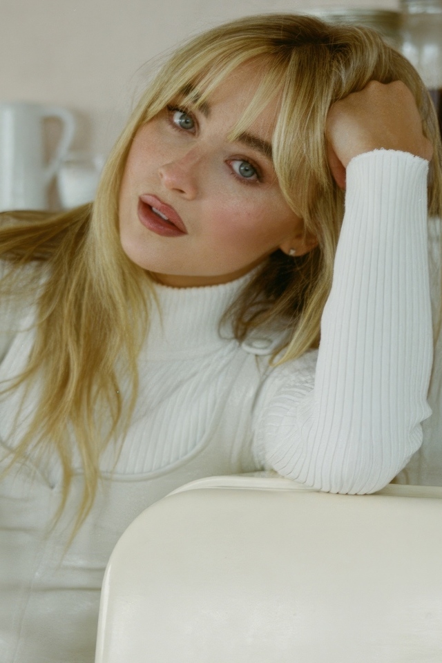 Молодая блондинка актриса Сабрина Карпентер сидит на столом