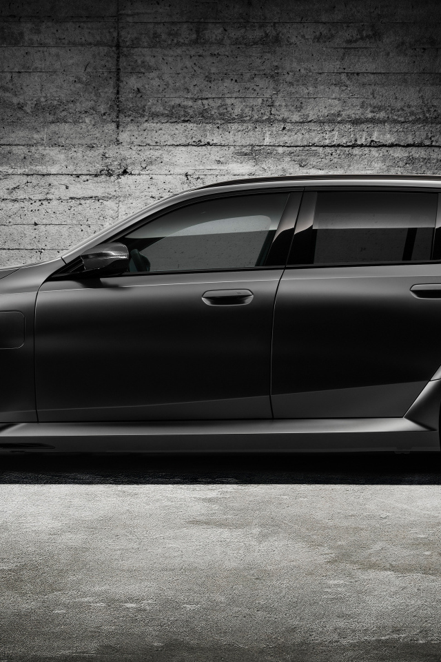 Вид сбоку на черный автомобиль BMW M5 Touring 2024 года