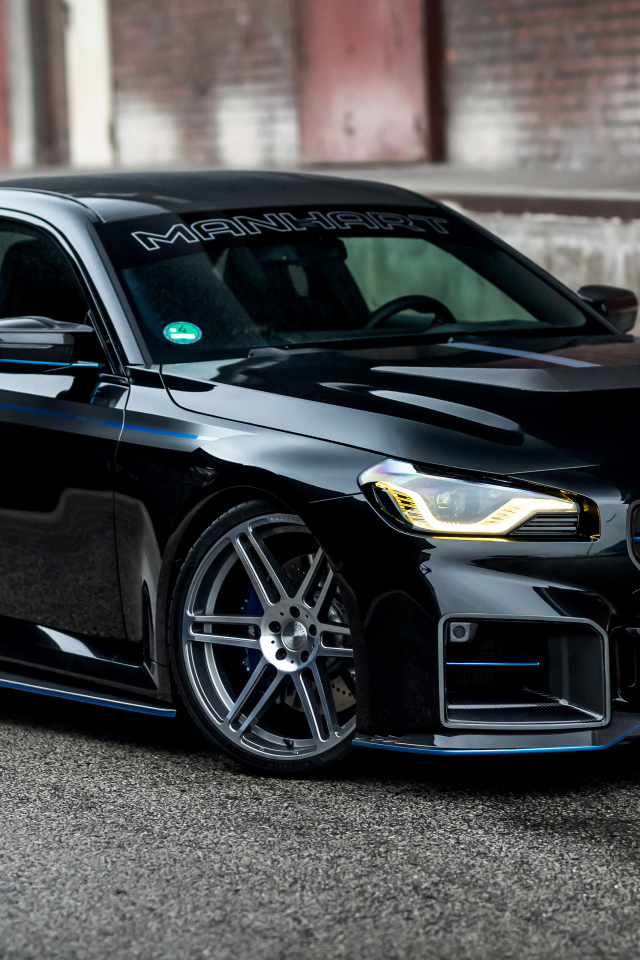 Черный автомобиль BMW M2 Manhart MH2 560 на сером фоне в городе