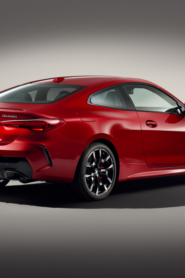 Красный автомобиль BMW M440i XDrive Coupé 2024 года на сером фоне