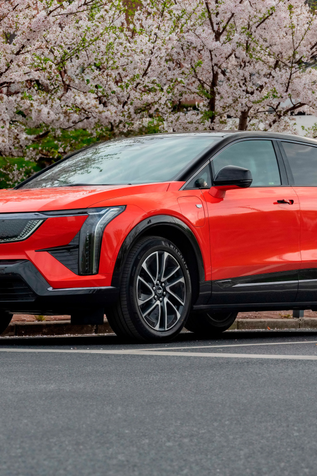 Красный Cadillac Optiq Sport 2024 года у цветущих деревьев