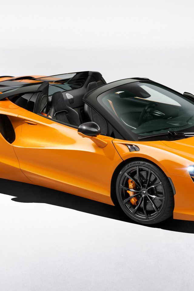 Оранжевый автомобиль McLaren Artura Spider на сером фоне