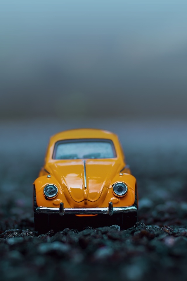 Маленькая игрушечная машинка стоит на асфальте