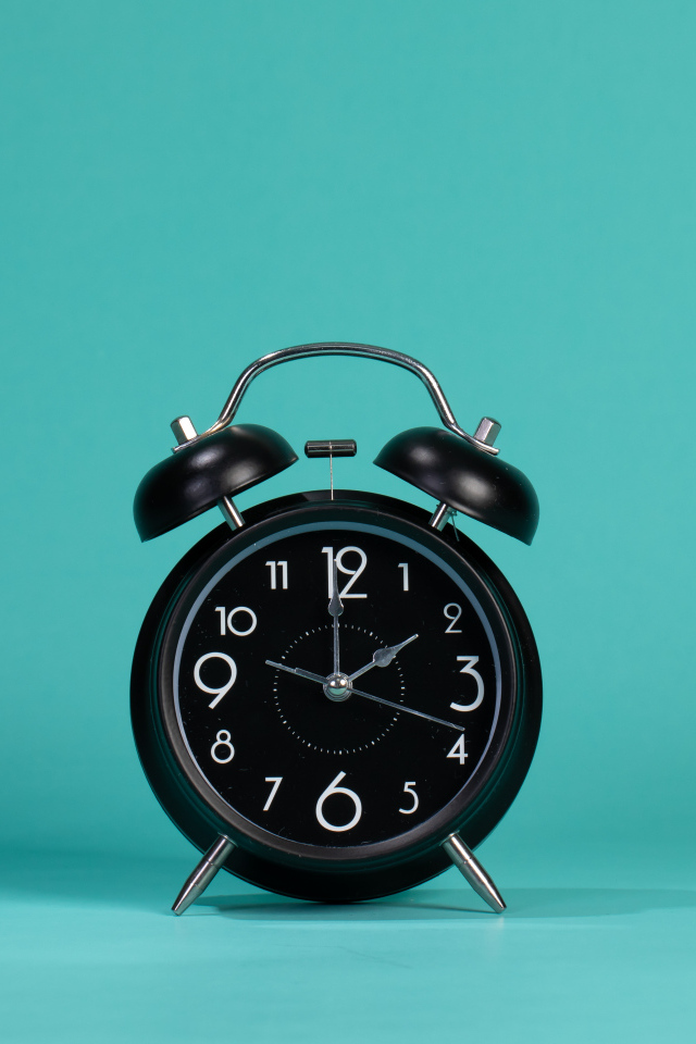 Черный будильник на голубом фоне
