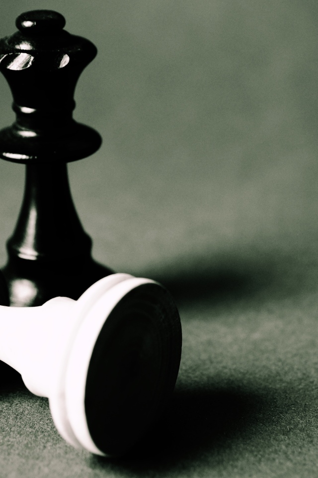 Черная и белая шахматные фигуры на сером столе