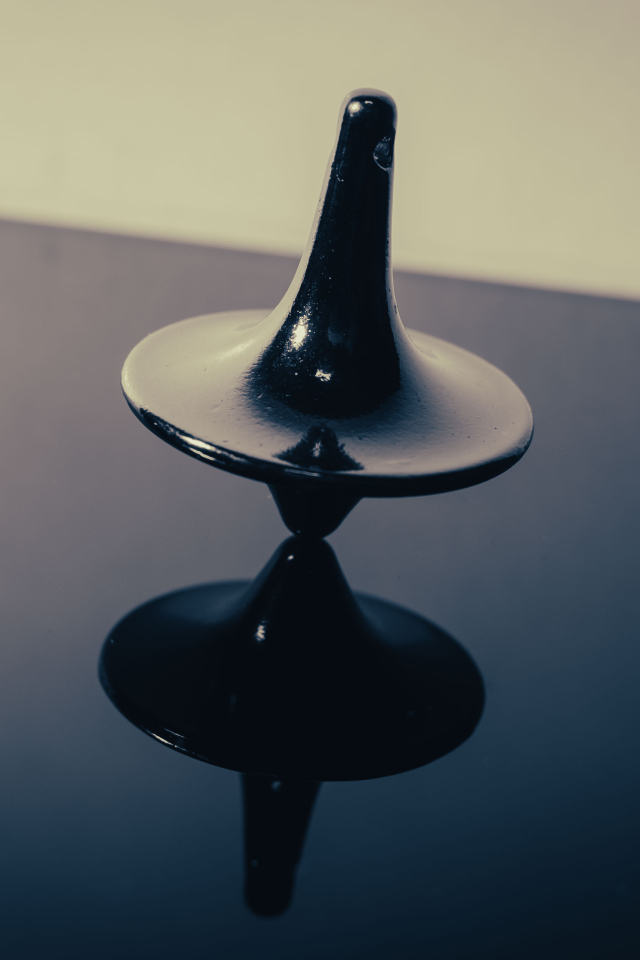 Черный волчок на ровной поверхности