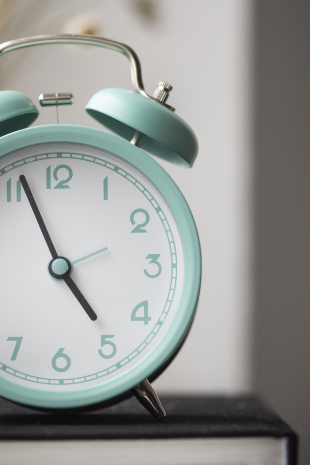 Голубой будильник стоит на книге в комнате