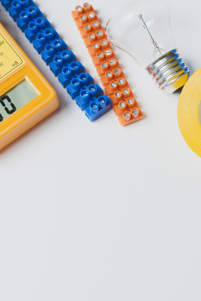 Электрическические приборы, мультиметр, изолента на сером фоне