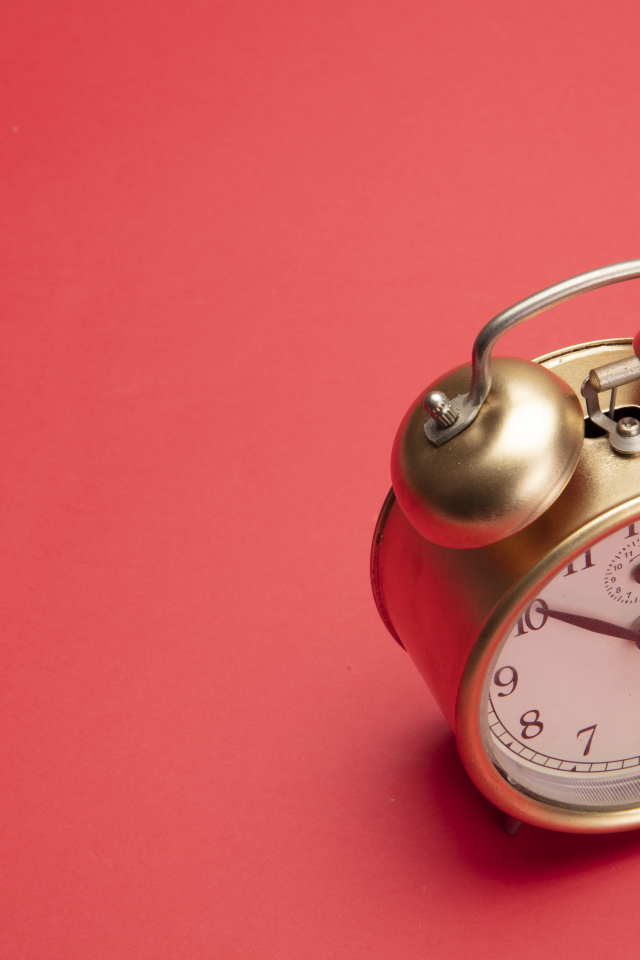 Золотой будильник на красном фоне