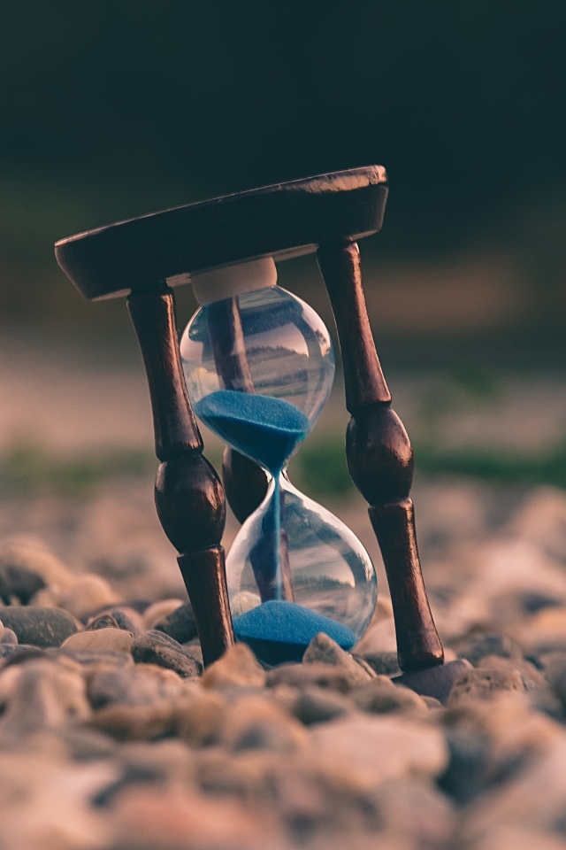 Песочные часы лежат на мелких камнях