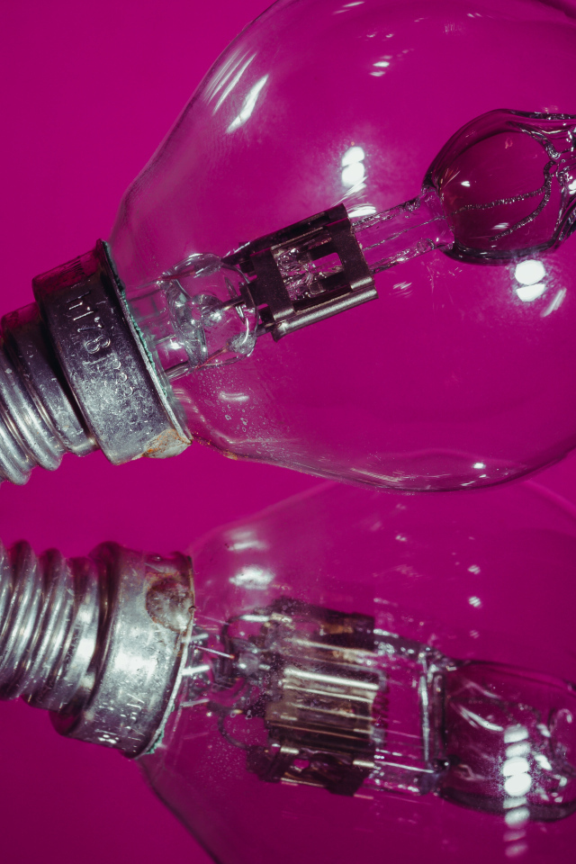 Лампочка отражается в поверхности на сиреневом фоне