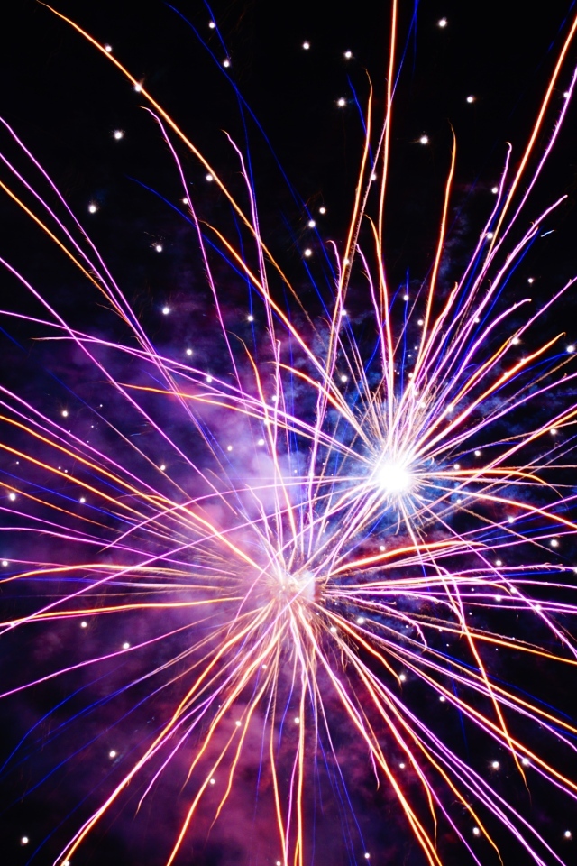 Разноцветные сиреневые искры фейерверка на черном фоне