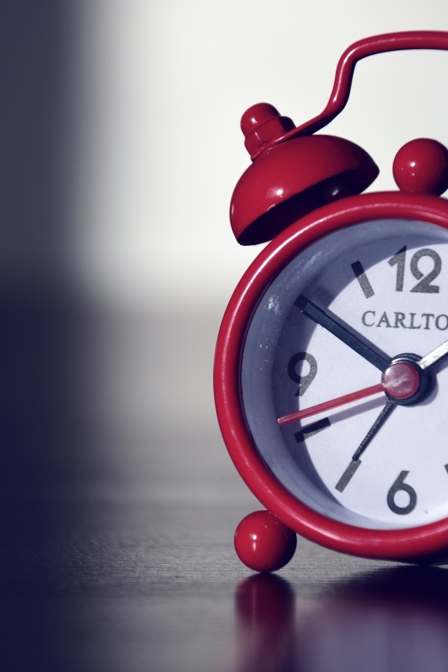 Красный будильник на черном столе
