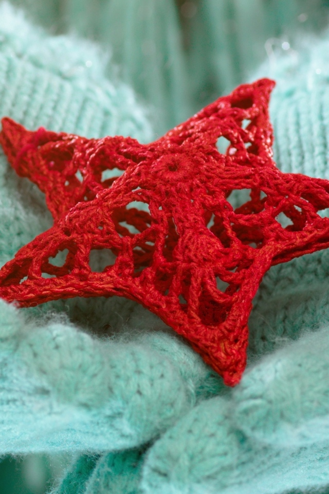 Красная вязаная звезда в руках в варежках