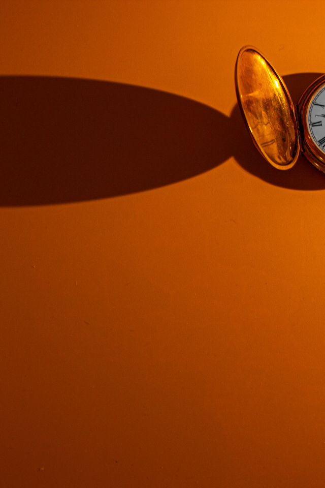 Тень от карманных часов на оранжевом фоне