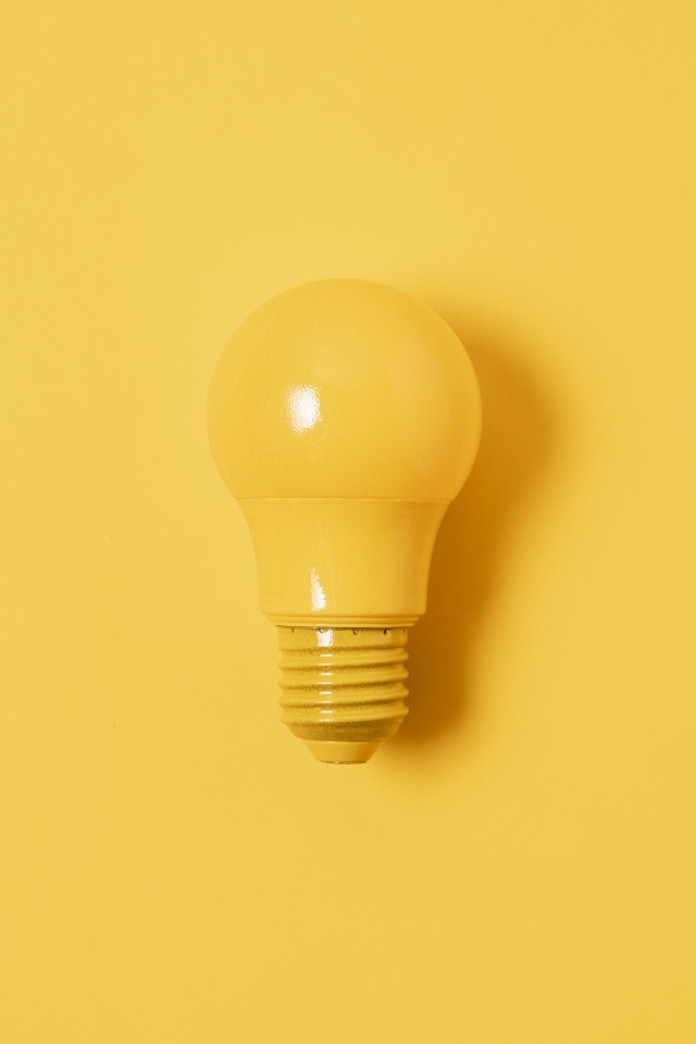 Желтая лампочка накаливания на желтом фоне