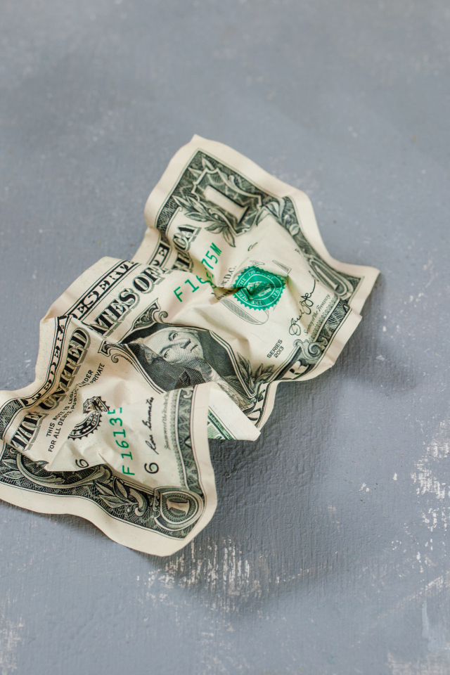 Смятая купюра один доллар на сером столе