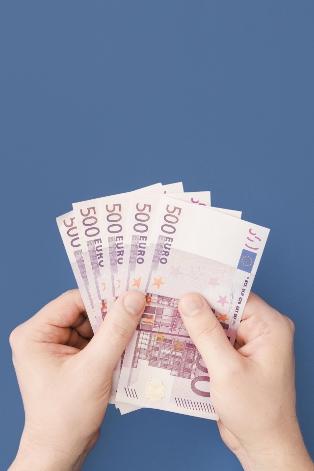 Купюры в пятьсот евро в руках на синем фоне