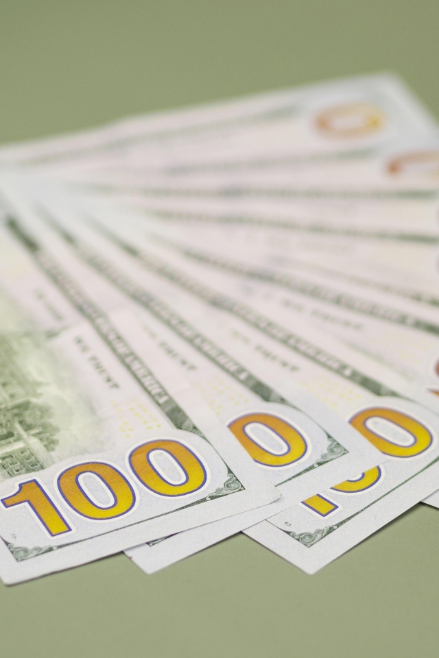 Пачка стодолларовых купюр на зеленом фоне