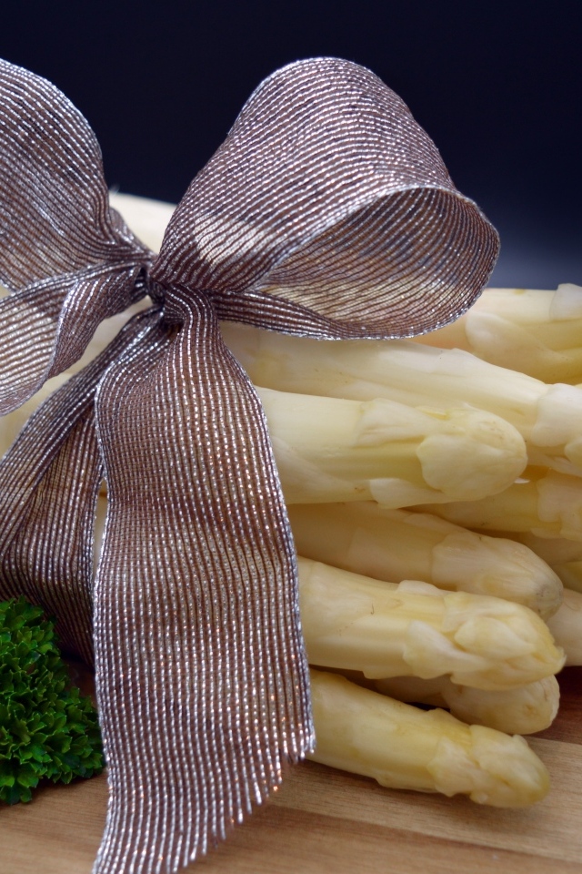 Спаржа с бантом на столе с петрушкой