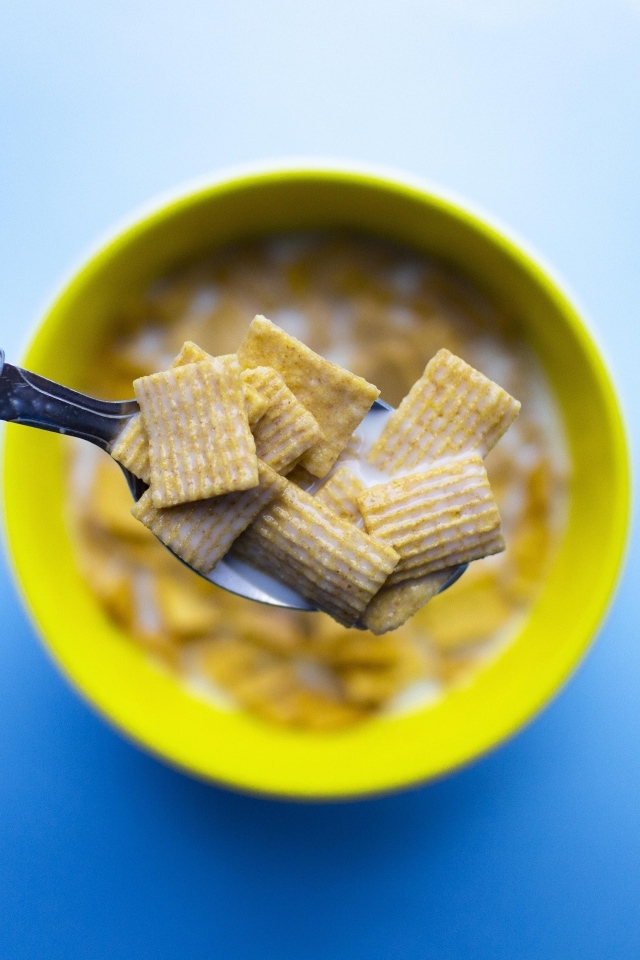 Хлопья с молоком на ложке на голубом фоне