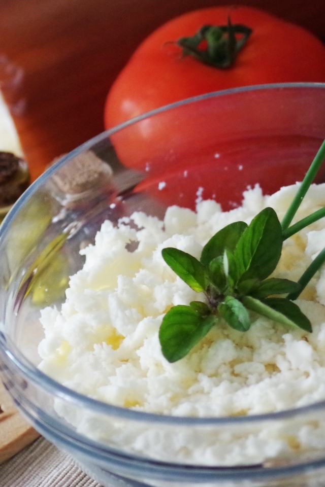 Творог в тарелке на столе с помидорами