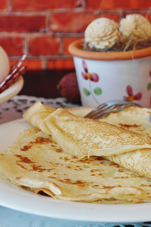 Delicious thin pancakes on the table with eggs
