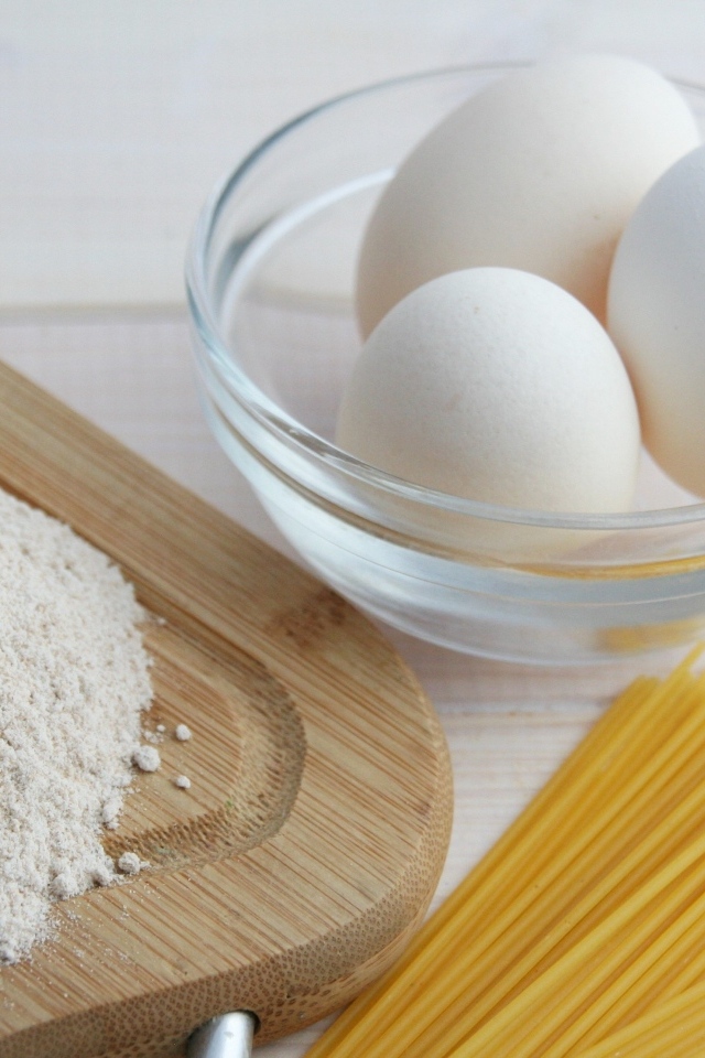 Яйца на столе с мукой и спагетти
