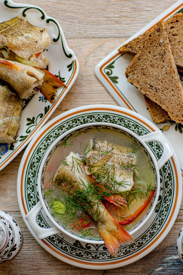 Уха на столе с хлебом и лимоном