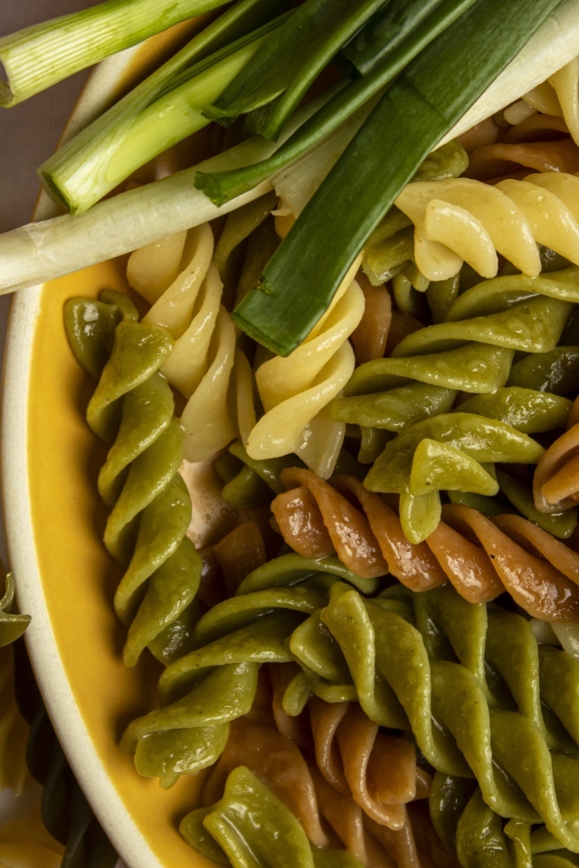 Разноцветные сваренные макароны с зеленым луком