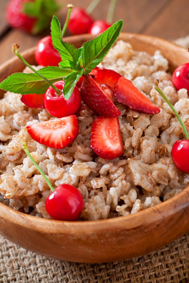 Овсяная каша с ягодами в деревянной миске