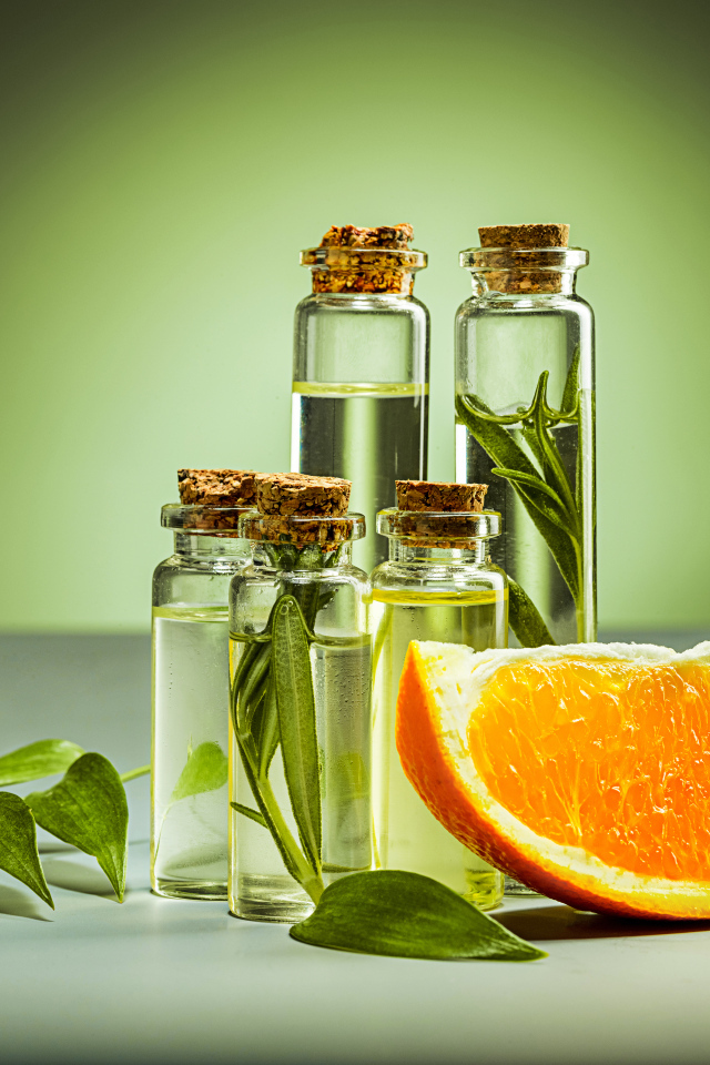 Апельсиновое масло на зеленом фоне с апельсинами