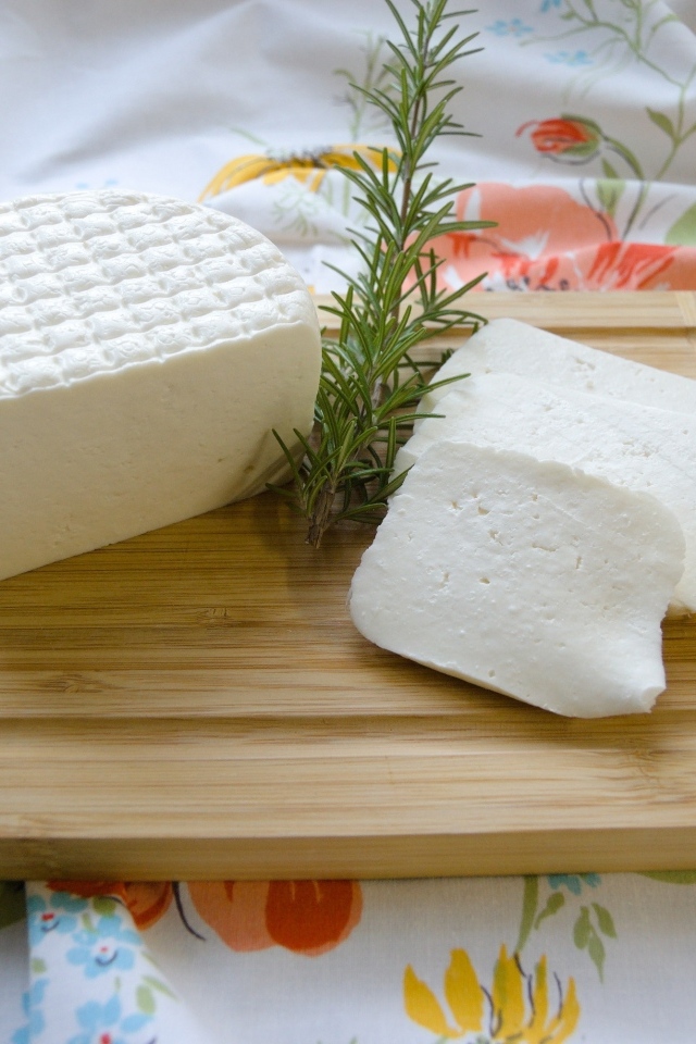 Кусок сыра с розмарином на разделочной доске