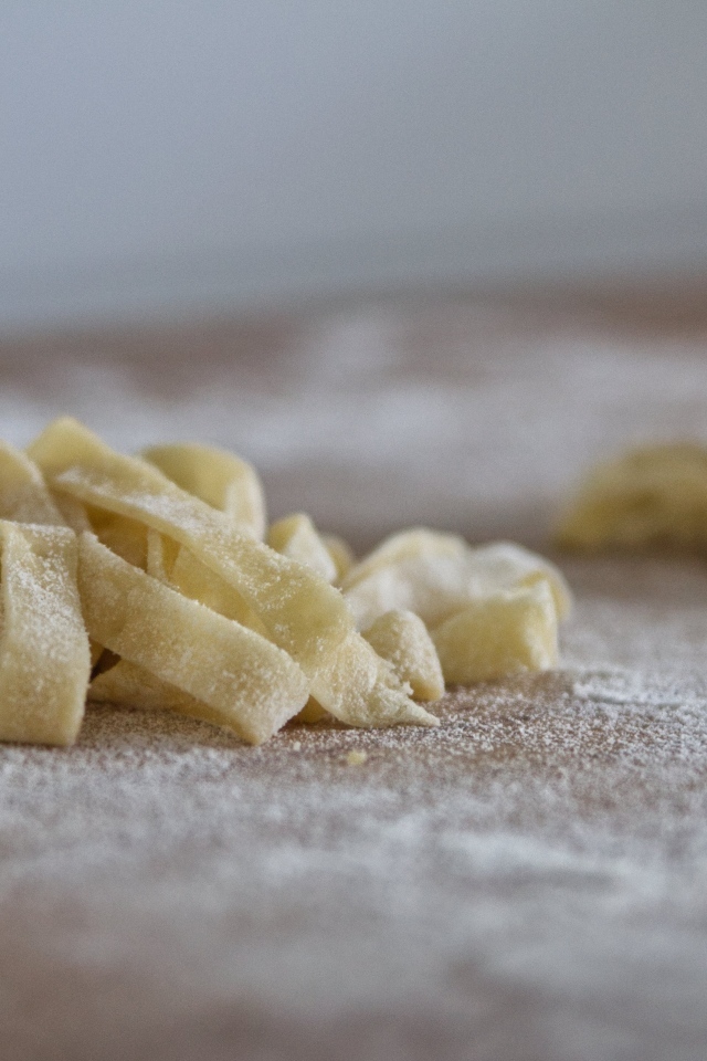 Сырое тесто для лапши на покрытом мукой столе