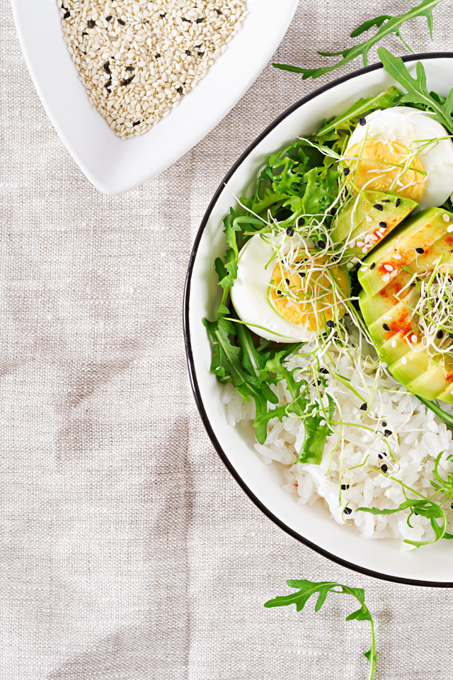 Рис с овощами и авокадо в тарелке