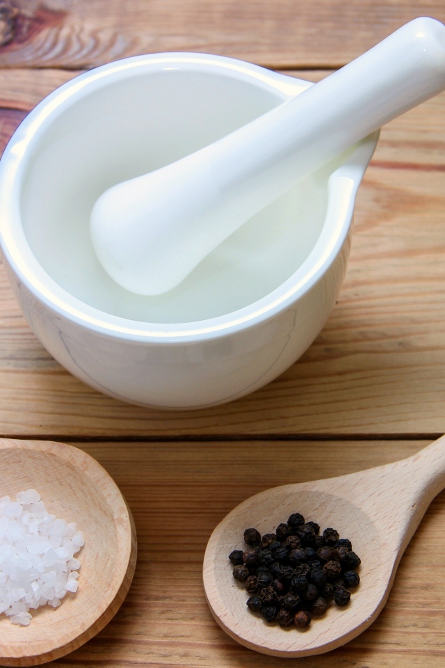 Соль с перцем на столе с деревянной ступкой