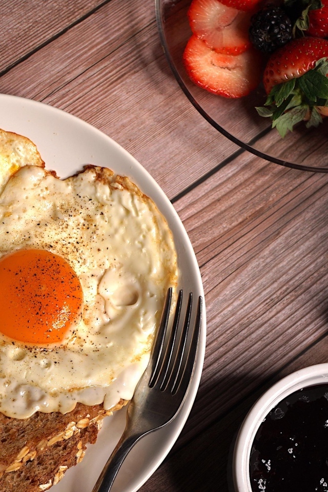 Яичница с гренками на столе с клубникой