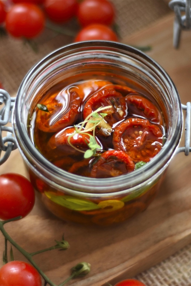 Вяленые томаты в масле в стеклянной банке на столе