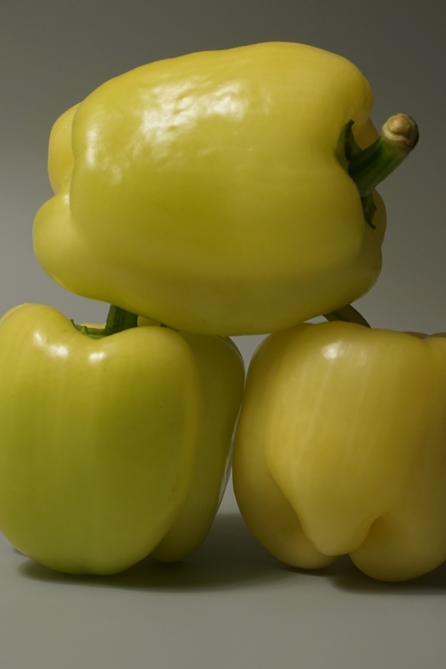 Три желтых перца на сером фоне