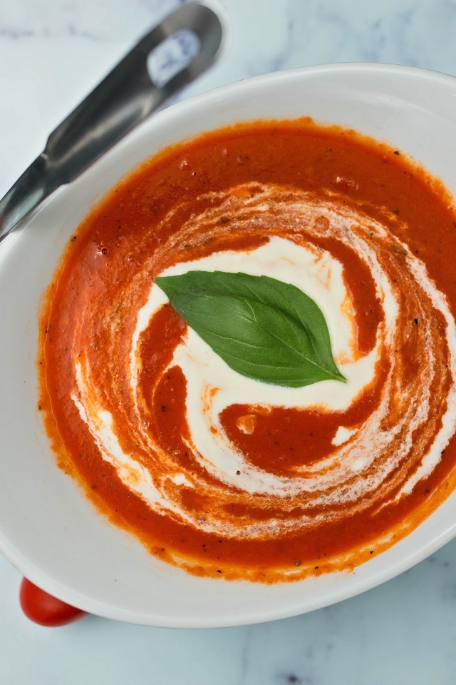 Томатный суп со сметаной в белой тарелке