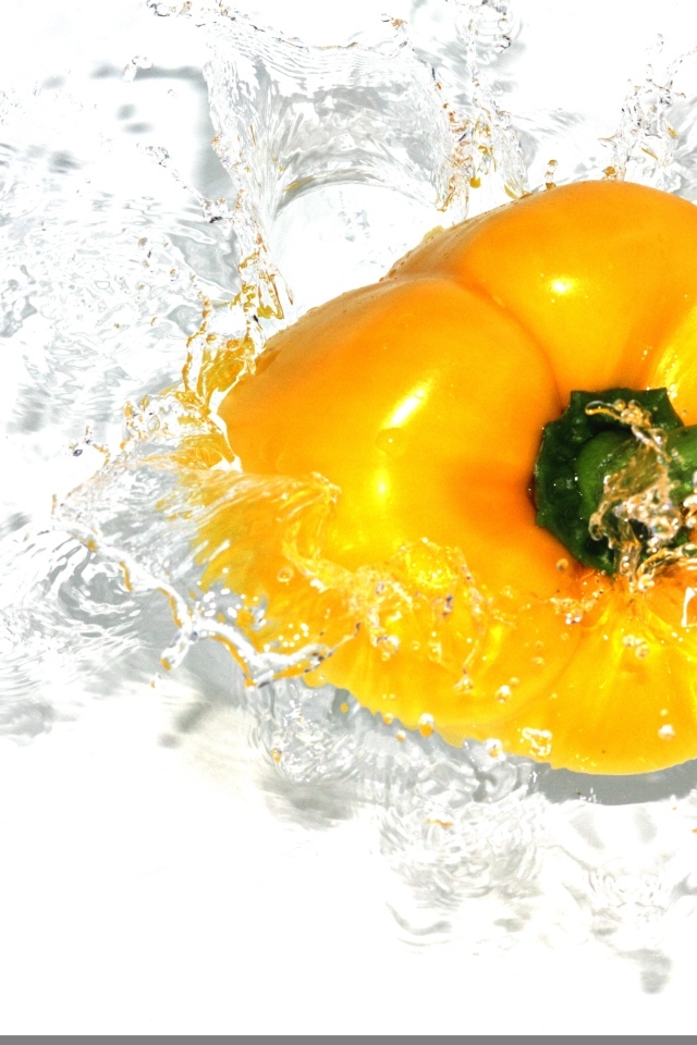 Желтый сладкий перец в воде на белом фоне