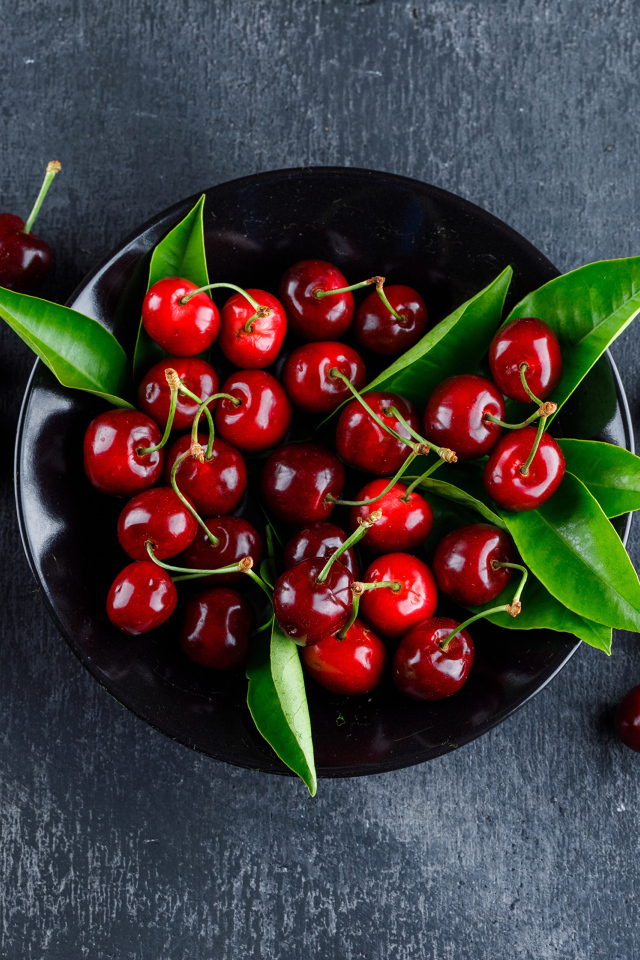 Черная  тарелка с красными ягодами черешни