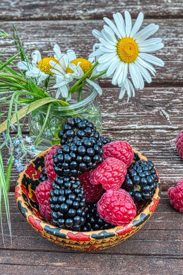 Ягоды черники и малины на столе с ромашками