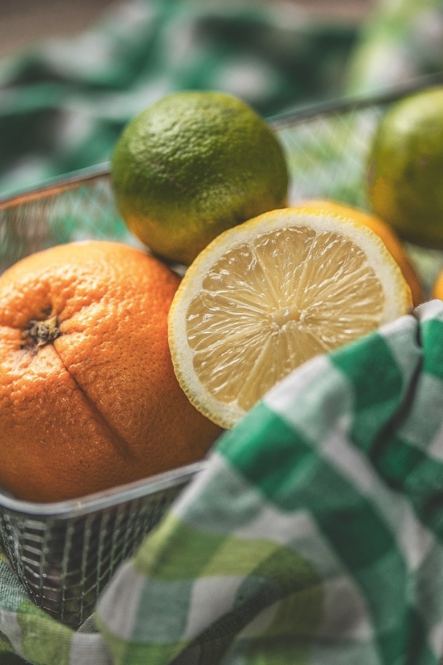 Цитрусовые фрукты в железной корзинке на столе